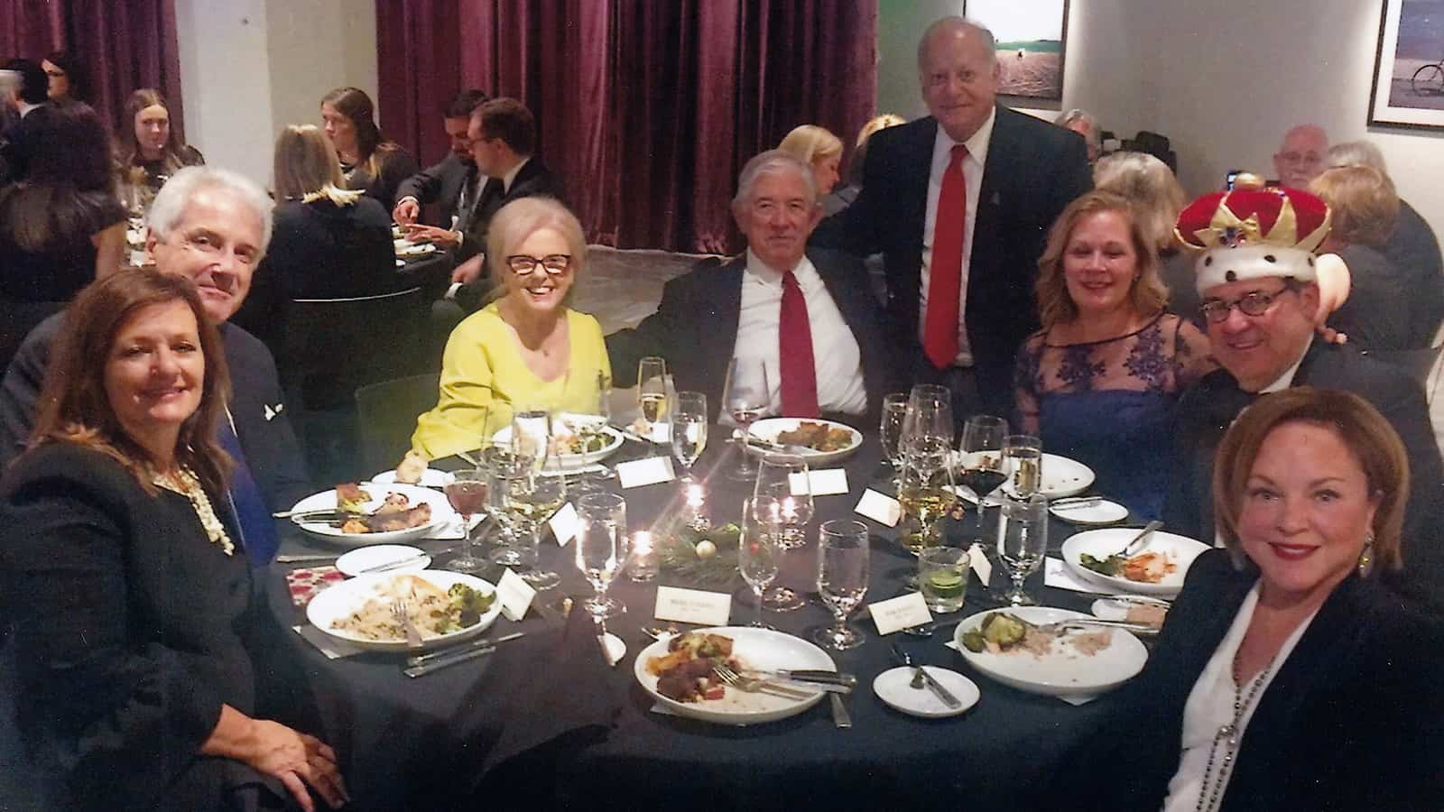 Photo of "Dirt King" Joe Lewallen sitting at the event with fellow McAfee & Taft attorneys and past "Dirt King" honorees along with their spouses.