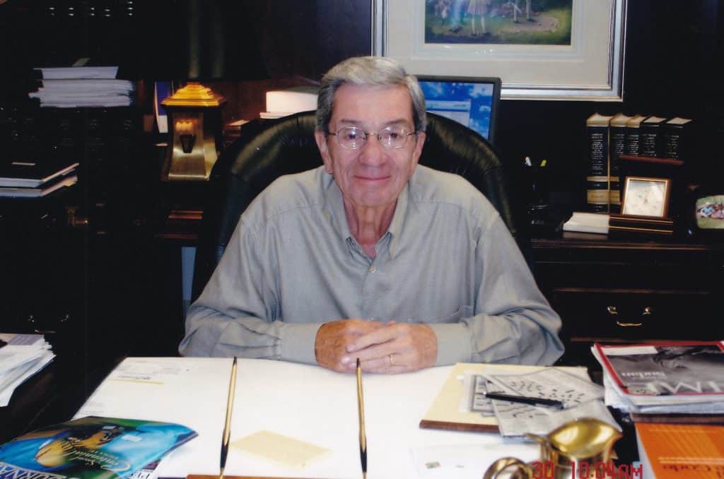 Photo of John Mee sitting at his desk in 2004