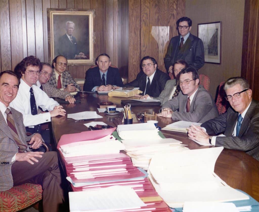 Photo of John Mee (standing) in the McAfee & Taft boardroom for the 1976 closing of the $50 million acquisition by merger of Lee Way Motor Freight by Pepsi Co.